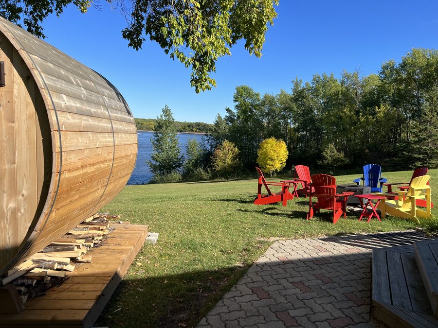 The cedar sauna, fire pit and Adirondack chairs on the lawn by the water